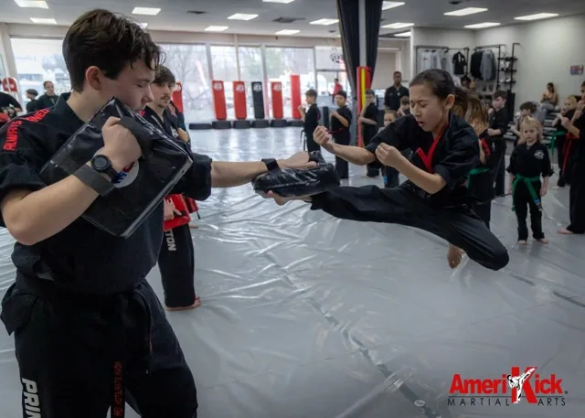Amerikick Pennington student landing a flying side kick on a partner's pad